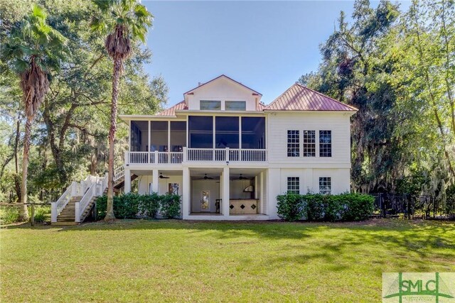 rear view of house with fence, a yard, stairway, a ceiling fan, and a sunroom