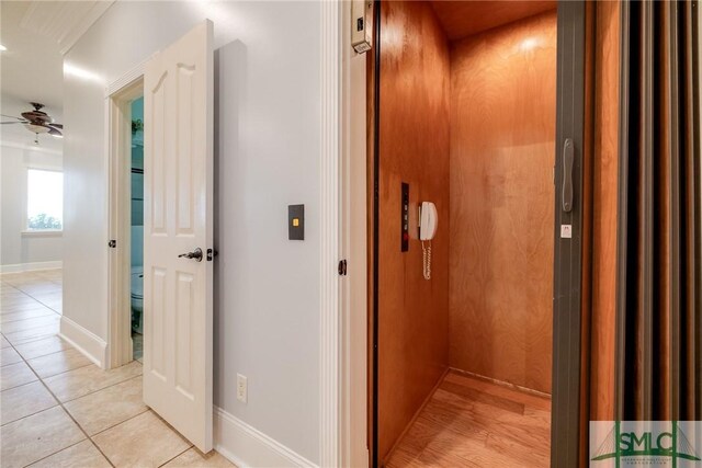 corridor with baseboards, elevator, and light tile patterned flooring