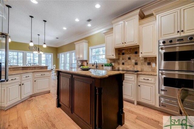 kitchen with light wood-style flooring, double oven, crown molding, a kitchen island, and tasteful backsplash