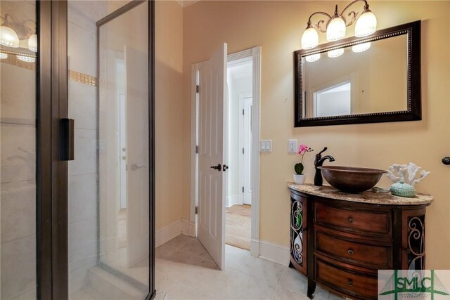 bathroom featuring baseboards, tile patterned flooring, vanity, and a shower with shower door