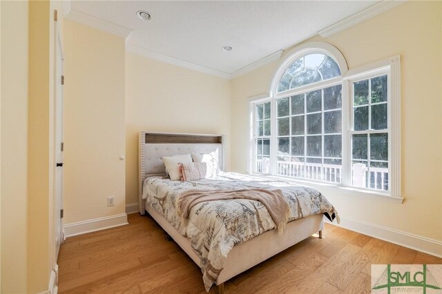 bedroom with ornamental molding, baseboards, and light wood-type flooring