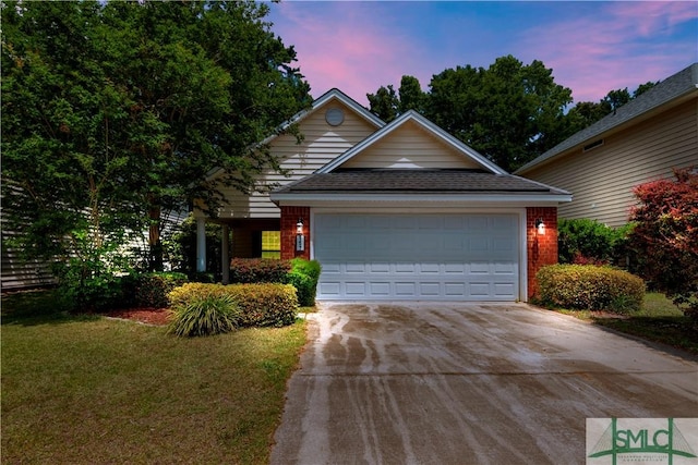 view of front of house with a yard, concrete driveway, a garage, and brick siding