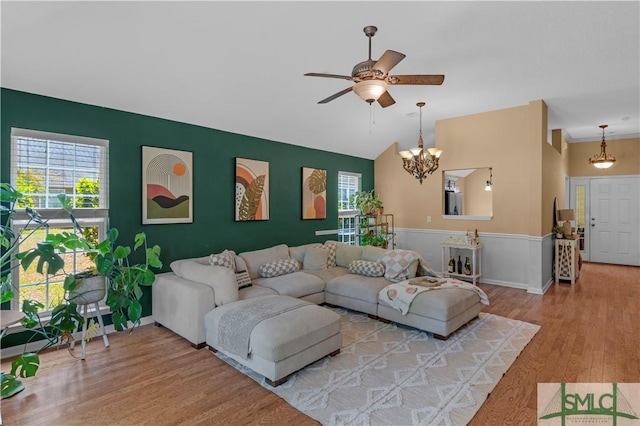 living room with baseboards, ceiling fan with notable chandelier, light wood-type flooring, and plenty of natural light