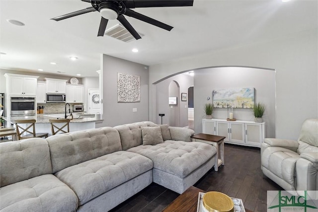 living room featuring dark wood finished floors, visible vents, ceiling fan, arched walkways, and recessed lighting