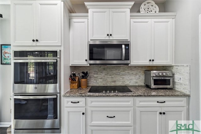 kitchen featuring dark stone countertops, appliances with stainless steel finishes, decorative backsplash, and white cabinetry