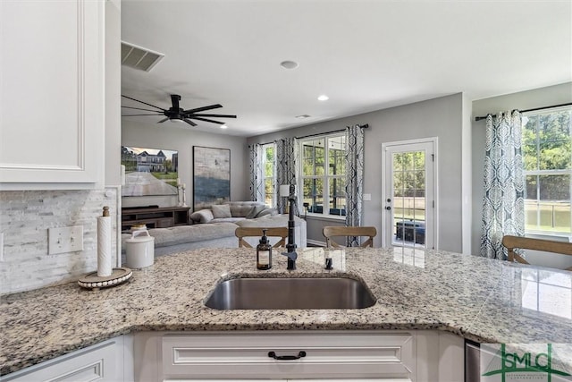 kitchen featuring a sink, light stone countertops, visible vents, and white cabinets