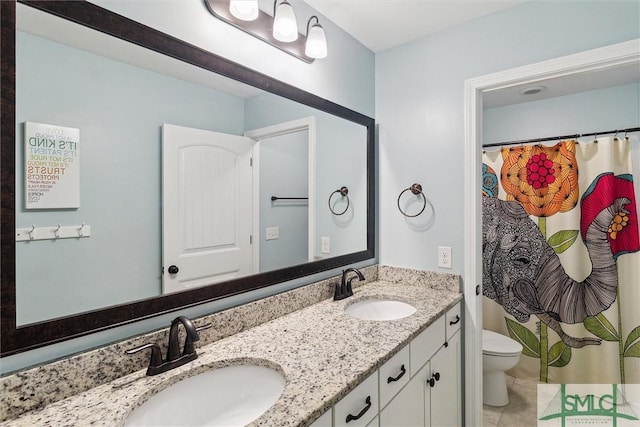 full bathroom featuring toilet, tile patterned flooring, double vanity, and a sink