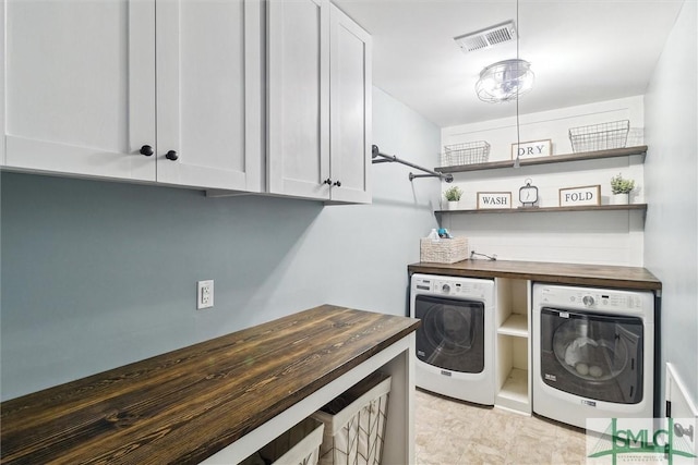 washroom featuring separate washer and dryer, cabinet space, and visible vents