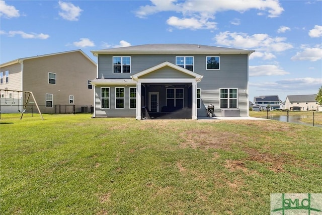 rear view of house featuring a sunroom, a playground, fence, and a lawn