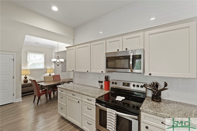 856 E 35th St, Savannah, GA 31401 - kitchen with stainless steel appliances, an inviting chandelier, light wood finished floors, white cabinetry, and decorative backsplash