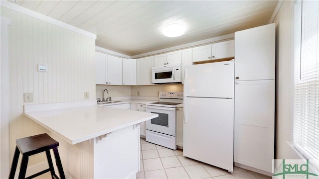 856 E 35th St, Savannah, GA 31401 - kitchen featuring a peninsula, white appliances, a breakfast bar, light countertops, and light tile patterned floors