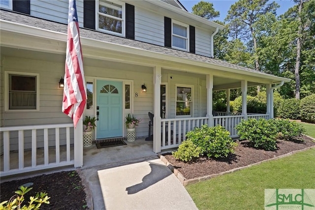 entrance to property featuring a porch and a shingled roof