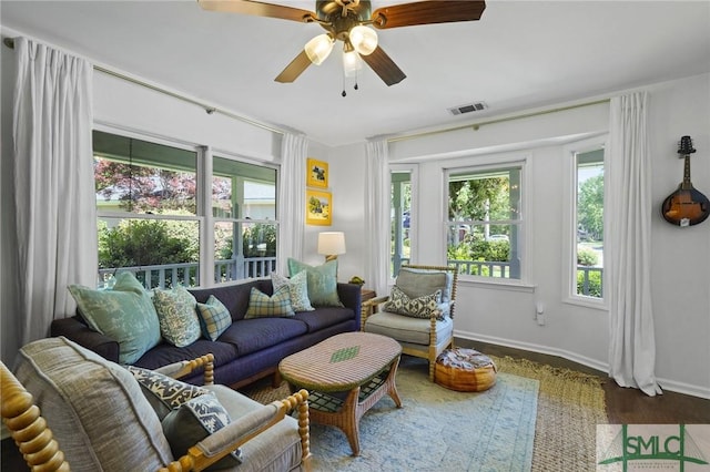 living room featuring baseboards, a ceiling fan, visible vents, and wood finished floors
