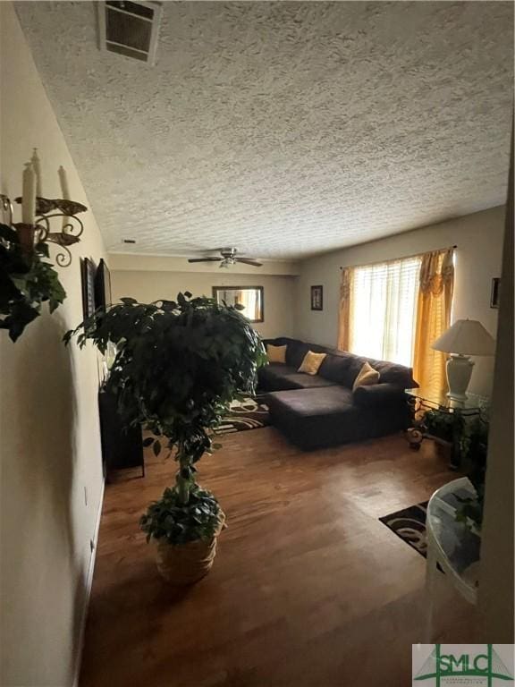 living area featuring a textured ceiling, visible vents, wood finished floors, and a ceiling fan