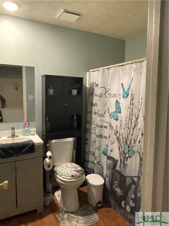 full bath featuring a textured ceiling, wood finished floors, vanity, and toilet