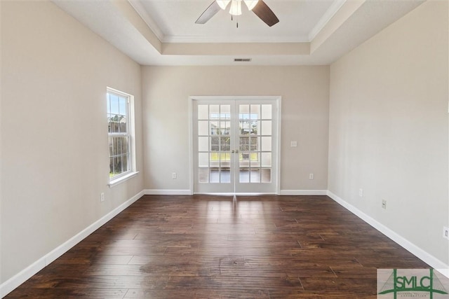 unfurnished room with a tray ceiling, visible vents, ornamental molding, and dark wood-style floors