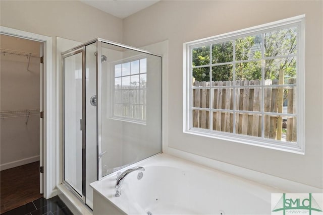 bathroom with a stall shower, a jetted tub, and a spacious closet