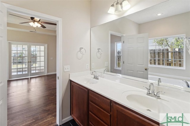bathroom with a sink, double vanity, baseboards, and wood finished floors