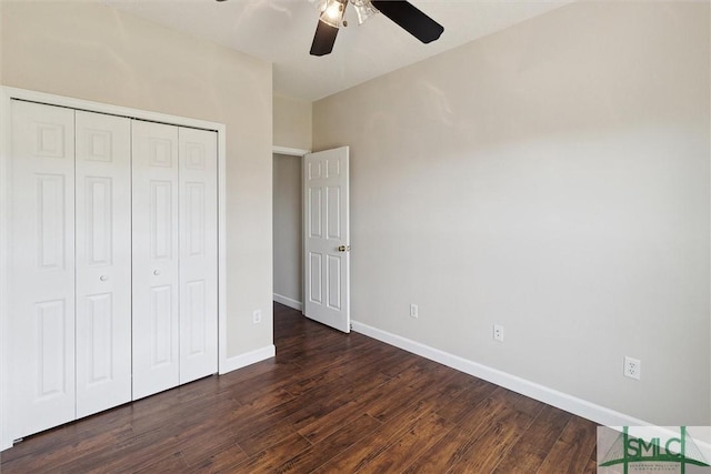 unfurnished bedroom with dark wood-style flooring, ceiling fan, a closet, and baseboards