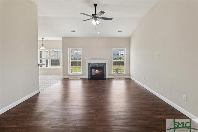 unfurnished living room featuring a ceiling fan, dark wood-style flooring, baseboards, and a fireplace with flush hearth