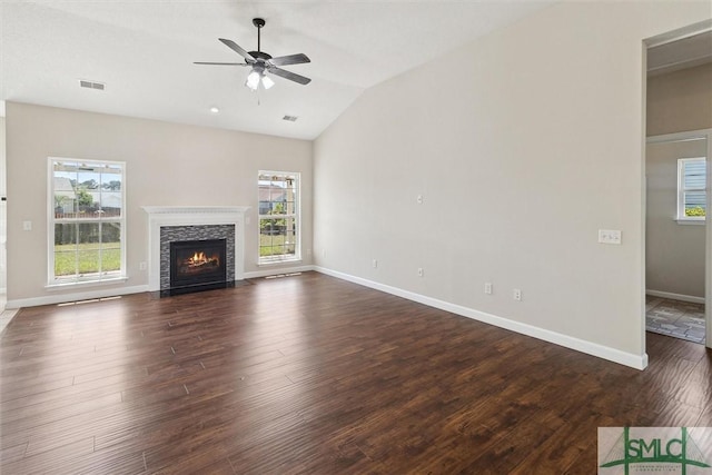 unfurnished living room with a ceiling fan, lofted ceiling, dark wood-style flooring, visible vents, and a fireplace with flush hearth
