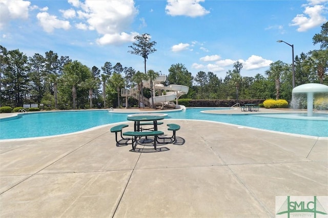 community pool with a patio and a water slide