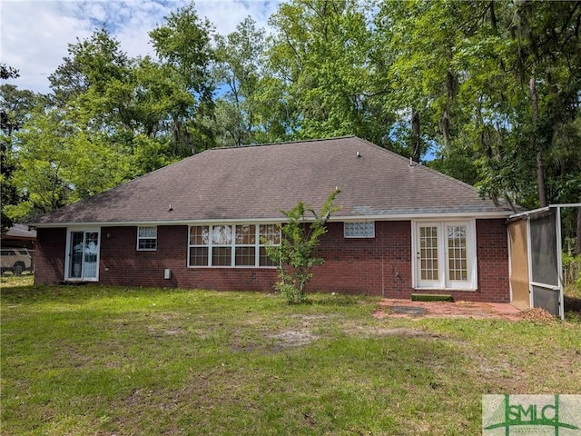 rear view of property with a shingled roof, a yard, and brick siding