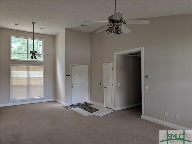 carpeted foyer with a textured ceiling, visible vents, baseboards, and ceiling fan