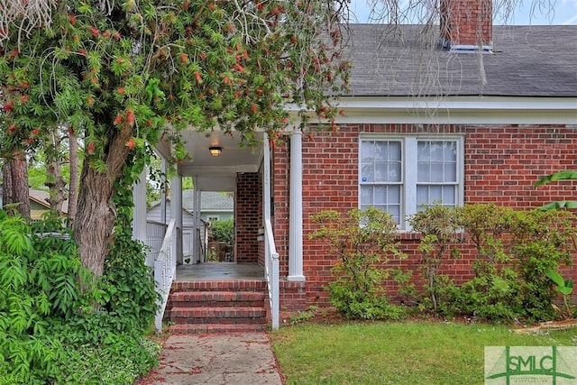 1020 Maupas Ave, Savannah, GA 31401 - view of exterior entry with covered porch, brick siding, roof with shingles, and a chimney
