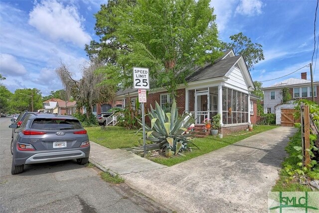 1020 Maupas Ave, Savannah, GA 31401 - view of front facade featuring a sunroom, a front lawn, and brick siding