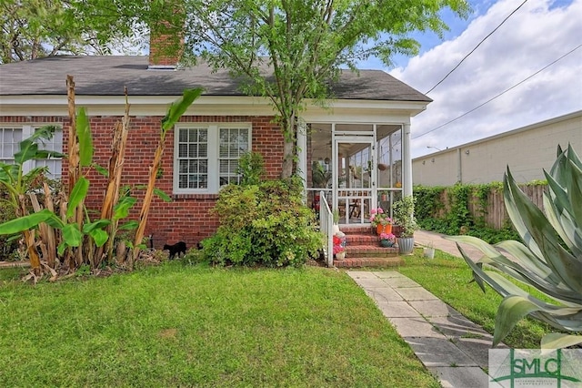 1020 Maupas Ave, Savannah, GA 31401 - back of house with a lawn, brick siding, fence, a sunroom, and roof with shingles