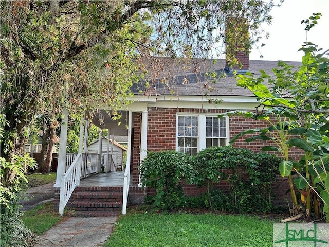 1020 Maupas Ave, Savannah, GA 31401 - view of front facade with brick siding, a chimney, a porch, roof with shingles, and a front yard