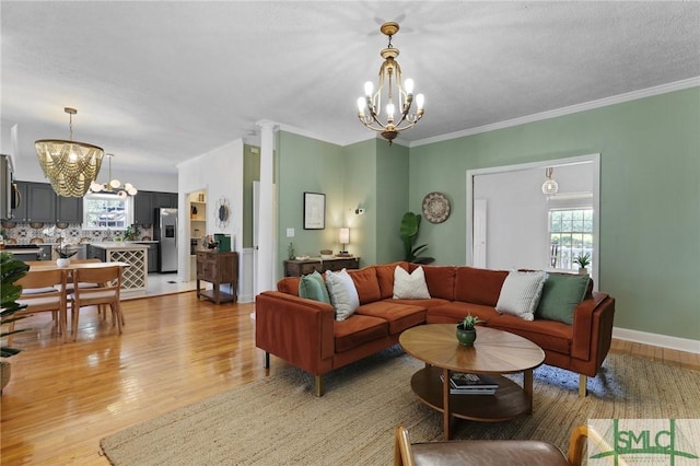 living room featuring a chandelier, light wood-type flooring, and ornamental molding