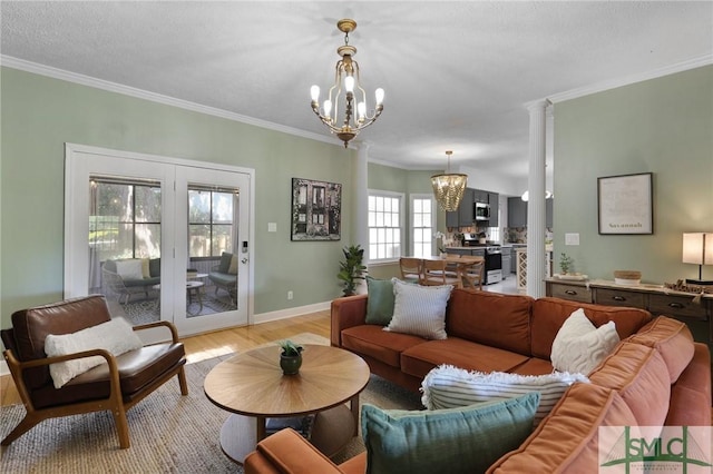 living room featuring a chandelier, light wood finished floors, ornamental molding, baseboards, and french doors