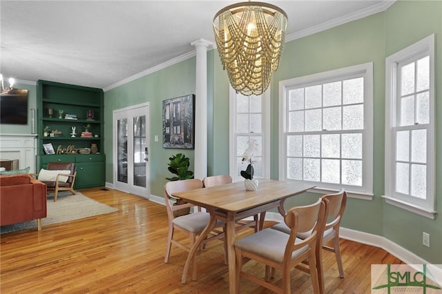 dining area featuring a chandelier, light wood-style flooring, ornamental molding, a premium fireplace, and baseboards