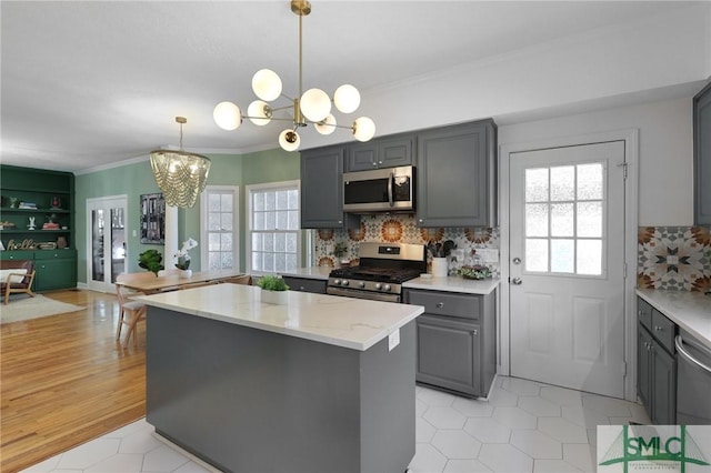 kitchen featuring stainless steel appliances, gray cabinets, a chandelier, a center island, and crown molding