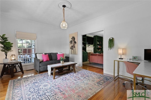 living room with wood finished floors, an office area, and ornamental molding