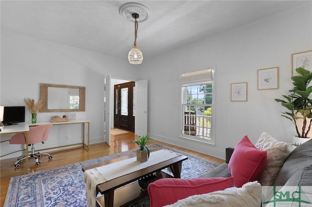 living area with a desk, wood finished floors, and baseboards