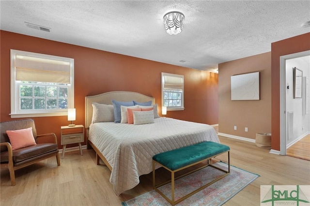 bedroom featuring a textured ceiling, light wood-style floors, and baseboards