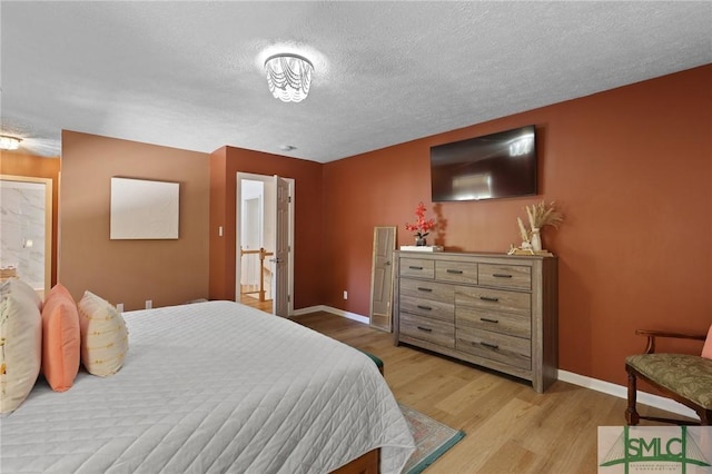 bedroom with light wood-type flooring, baseboards, and a textured ceiling