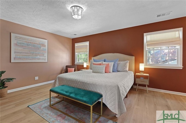 bedroom featuring a textured ceiling, wood finished floors, and baseboards