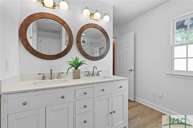 bathroom with double vanity, wood finished floors, and baseboards