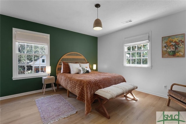 bedroom with wood finished floors, multiple windows, and baseboards
