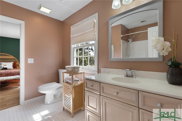 bathroom featuring toilet, baseboards, vanity, a shower, and ensuite bathroom
