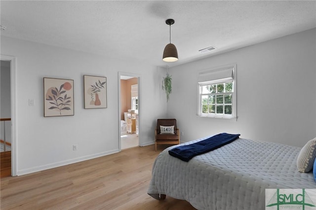 bedroom with light wood finished floors, baseboards, and a textured ceiling