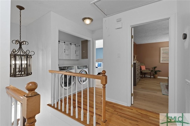hall with washing machine and dryer, wood finished floors, attic access, baseboards, and an upstairs landing