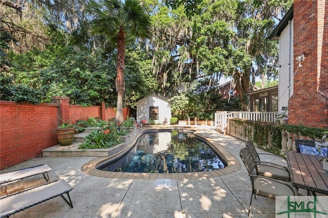 view of pool with a storage unit, a patio, an outdoor structure, and a fenced backyard