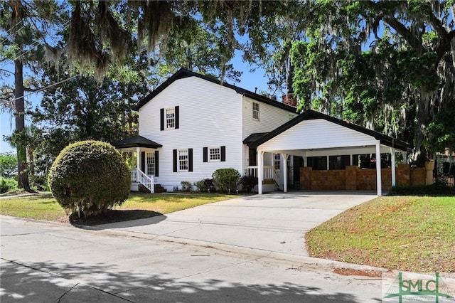 view of front facade with concrete driveway, a front yard, a chimney, and a carport