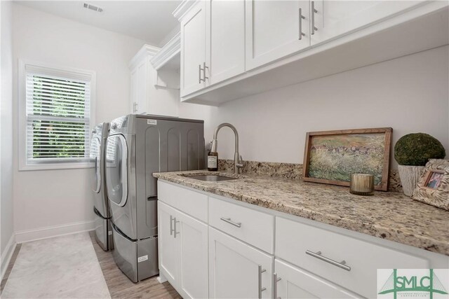195 Wildlife View Ct N, Richmond Hill, GA 31324 - clothes washing area with independent washer and dryer, cabinet space, baseboards, and light wood-style flooring