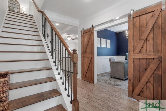195 Wildlife View Ct N, Richmond Hill, GA 31324 - stairs featuring a barn door, wood finished floors, wainscoting, crown molding, and ceiling fan